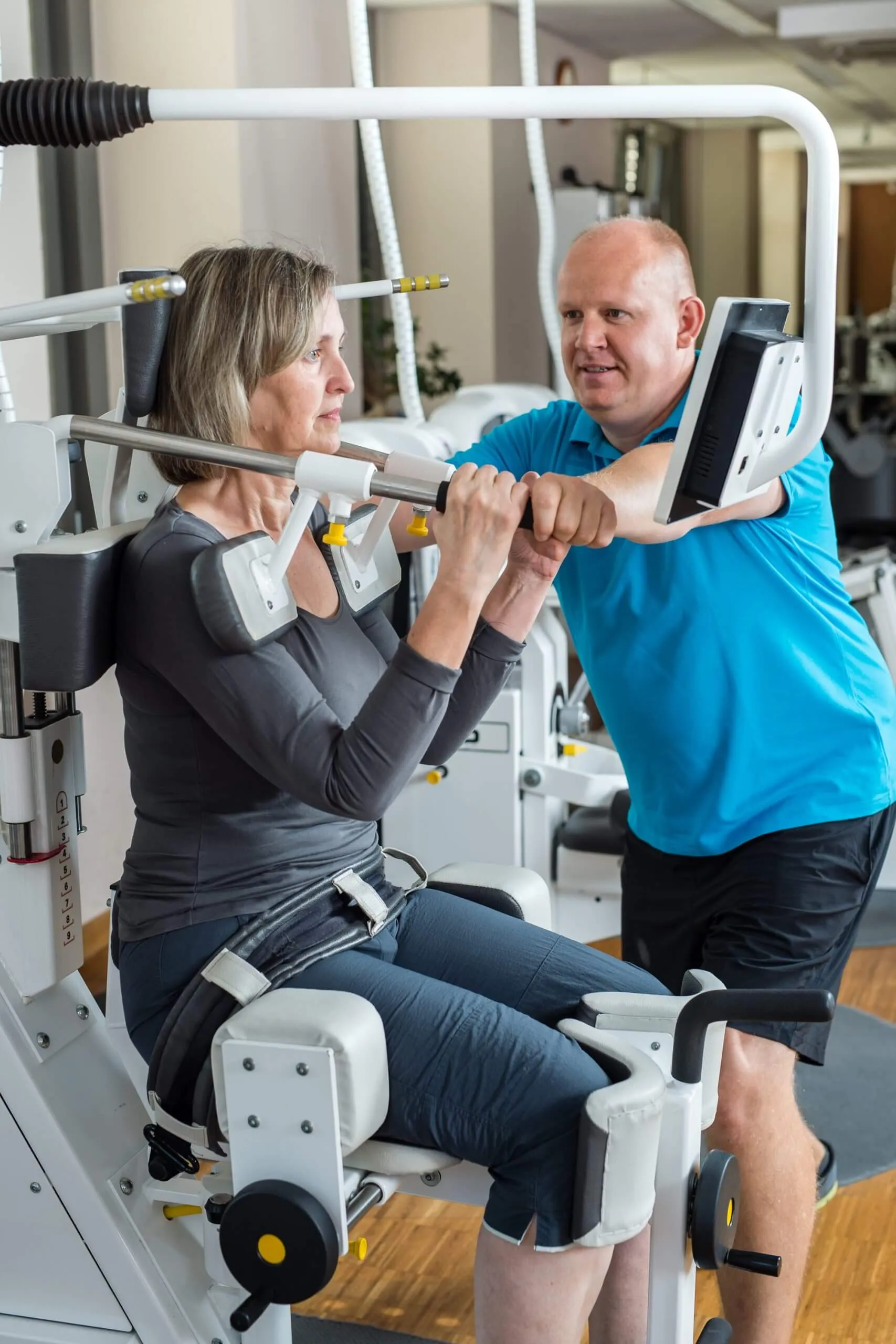 Therapeut betreut eine Patientin während des Trainings am Gerät