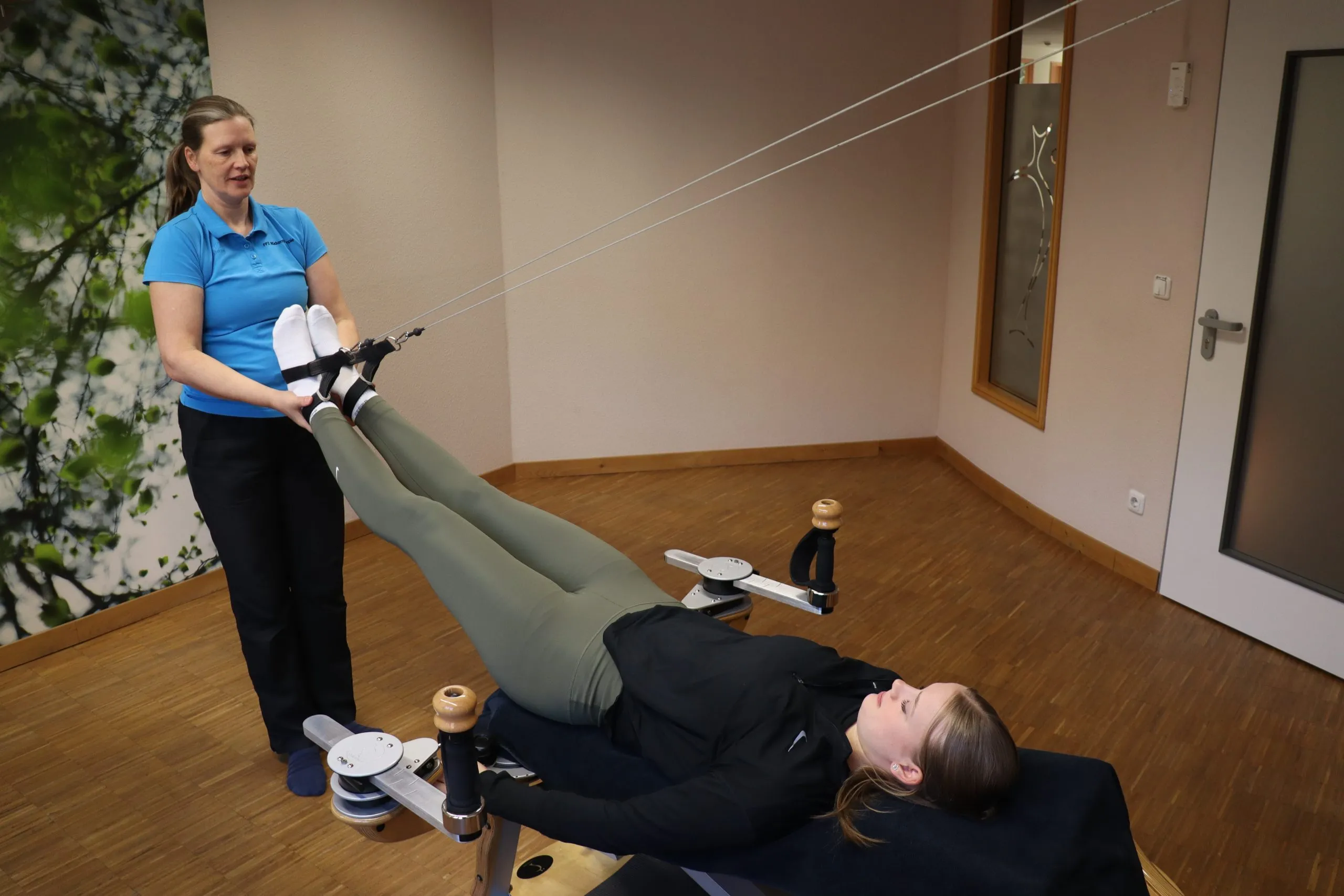 Therapeutin mobilisiert das Bein einer Patientin während einer Behandlung