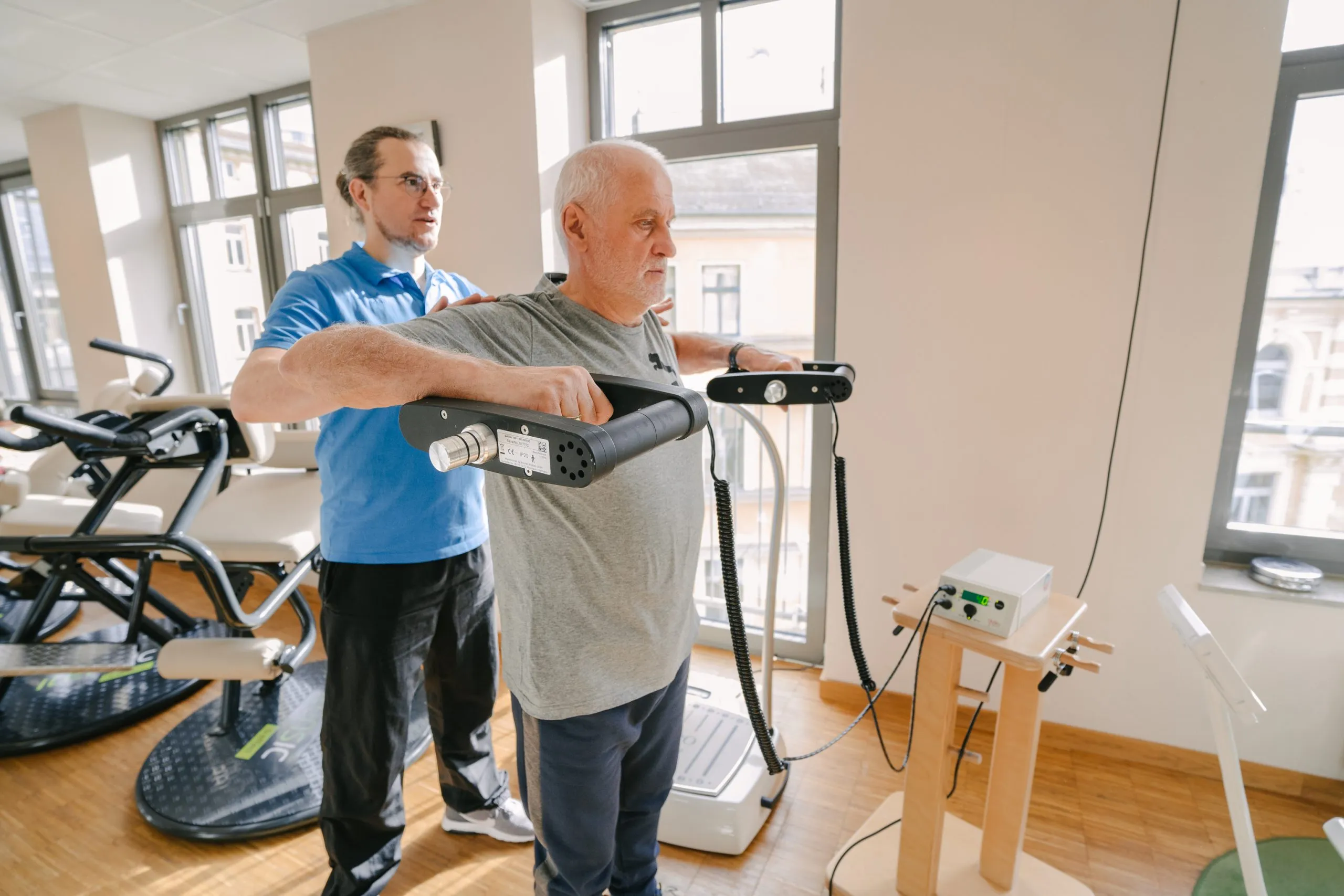 Therapeut erklärt einer Patientin die Einstellung an einem Trainingsgerät
